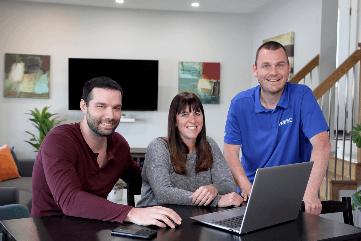 ViaNet technician assisting a family with internet setup on a laptop at home