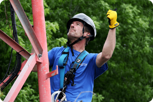 A technician working on a metal communications tower.